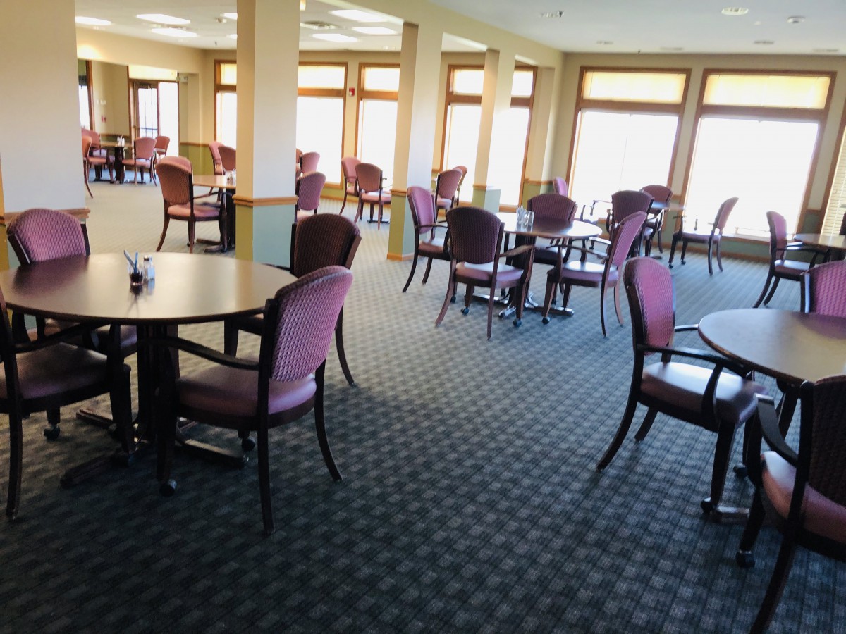Spacious dining area with multiple tables and chairs, featuring large windows.