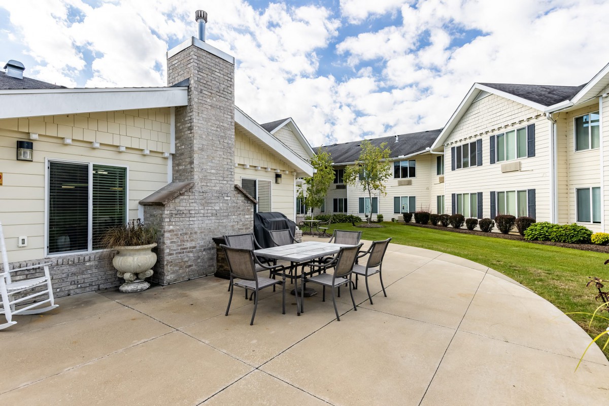 A spacious patio area with a table, chairs, and a chimney next to a residential building.