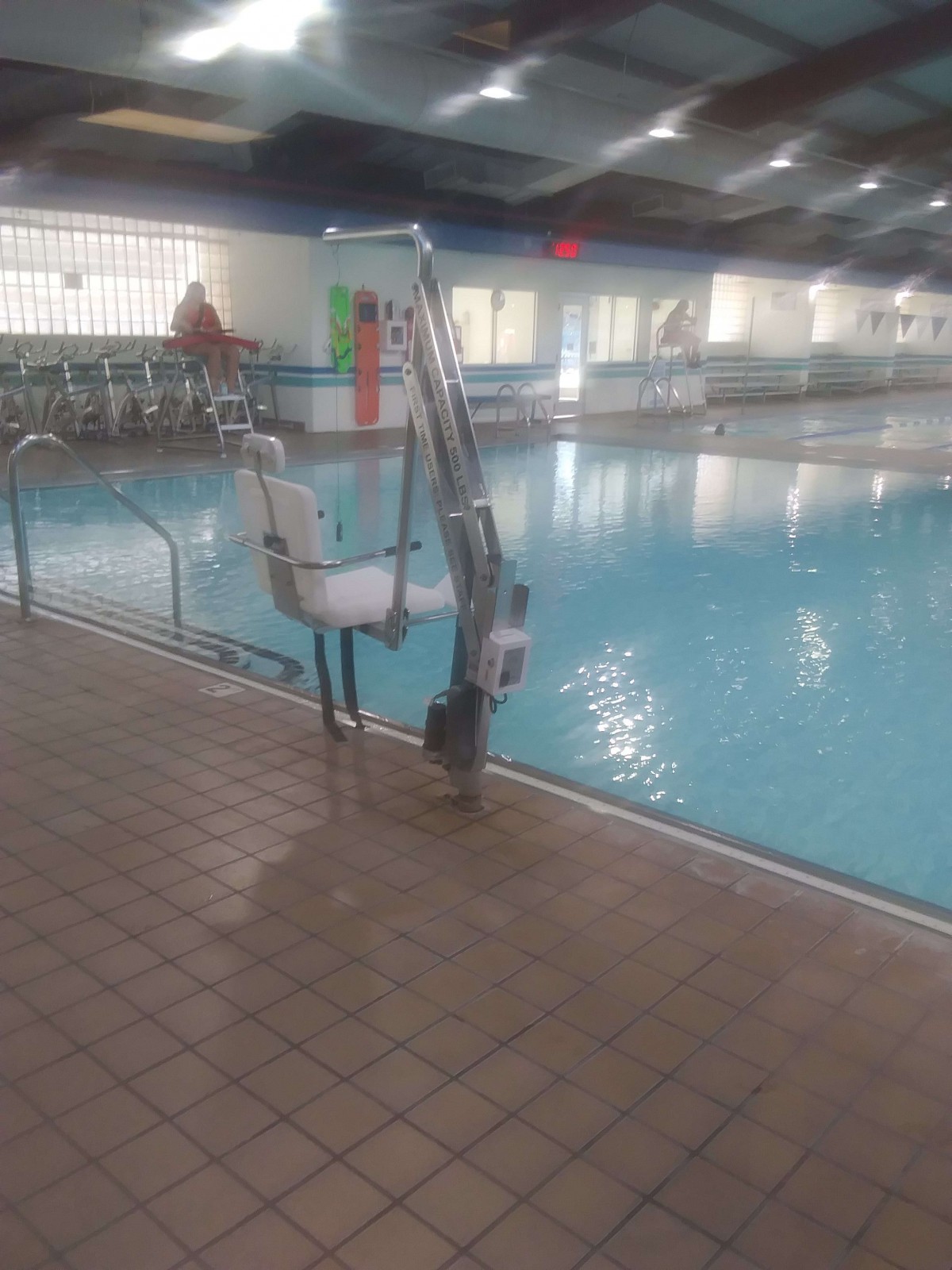 An indoor swimming pool featuring a pool lift for accessibility.