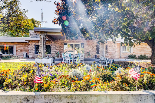 A sunny day in a vibrant garden with outdoor seating and an American flag, showcasing the beauty of nature.