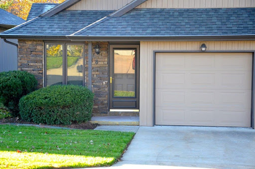 A charming house entrance featuring a well-maintained lawn and an attached garage.