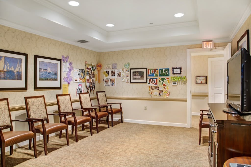 A cozy waiting room with chairs lined against the walls, decorated with colorful wall art and well-lit by ceiling lights.