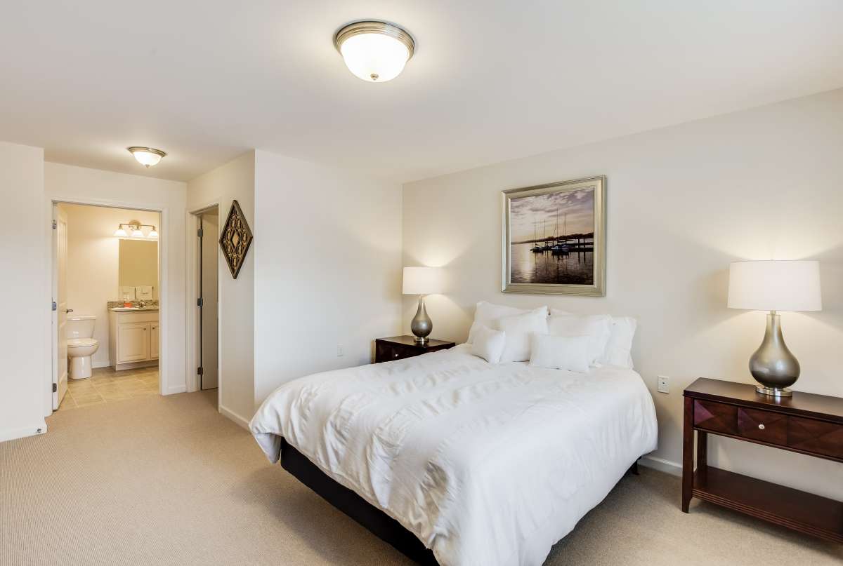 A cozy bedroom with a neatly made bed, bedside tables, and soft lighting.