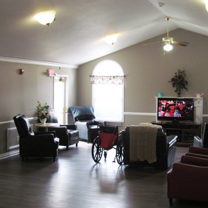 A cozy living room with a wheelchair, chairs, and a TV.