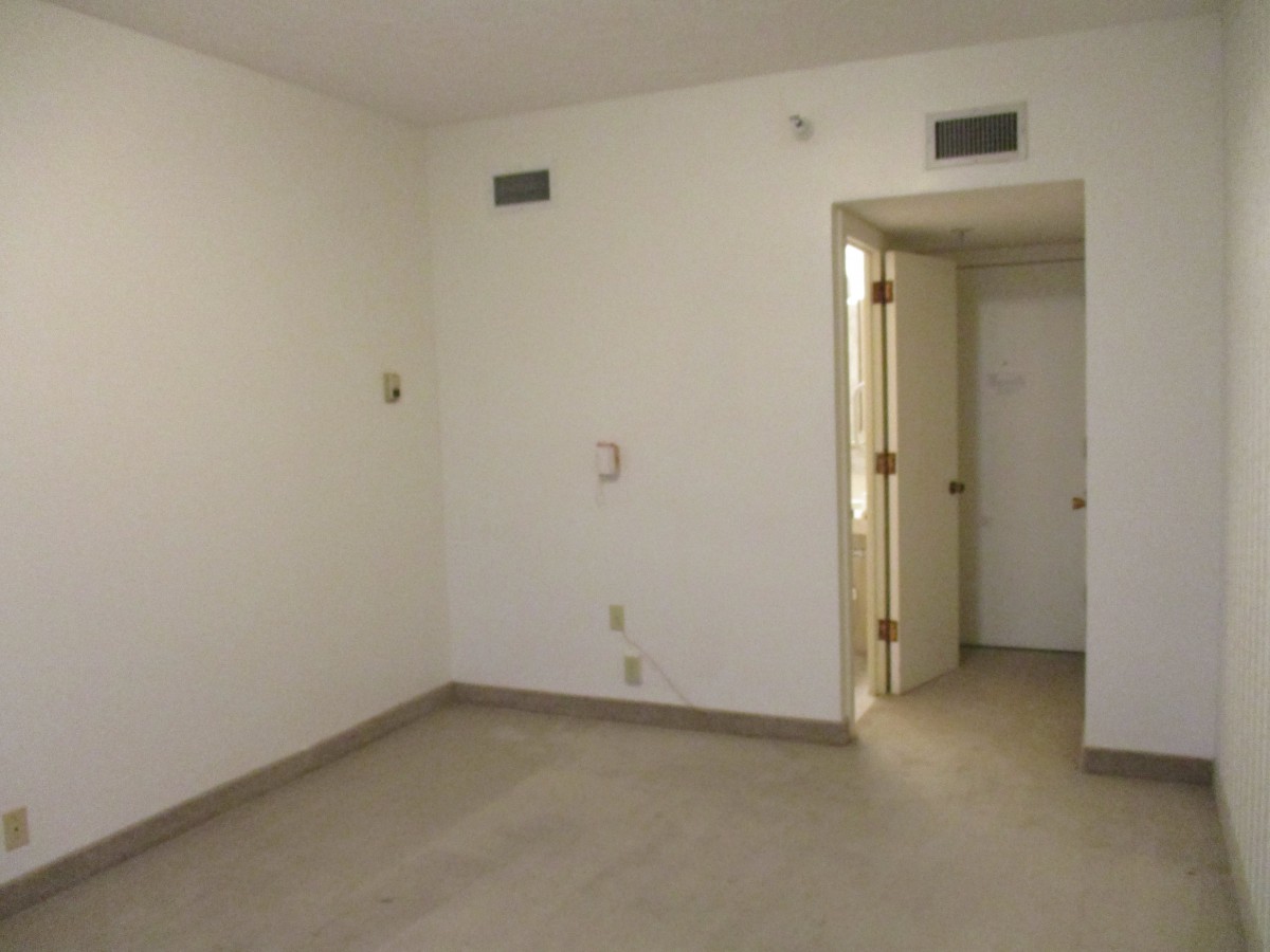 An empty room with white walls and a doorway leading to another space.