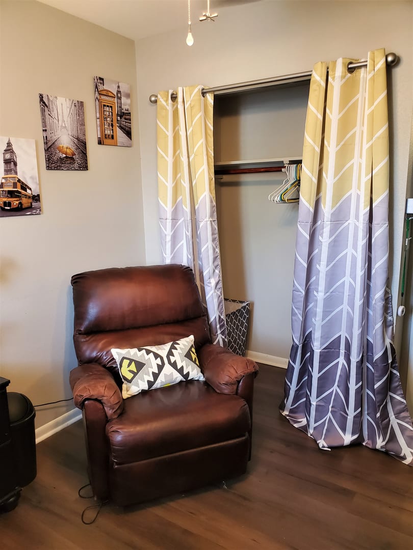 Cozy living room corner with a leather recliner and decorative curtains.