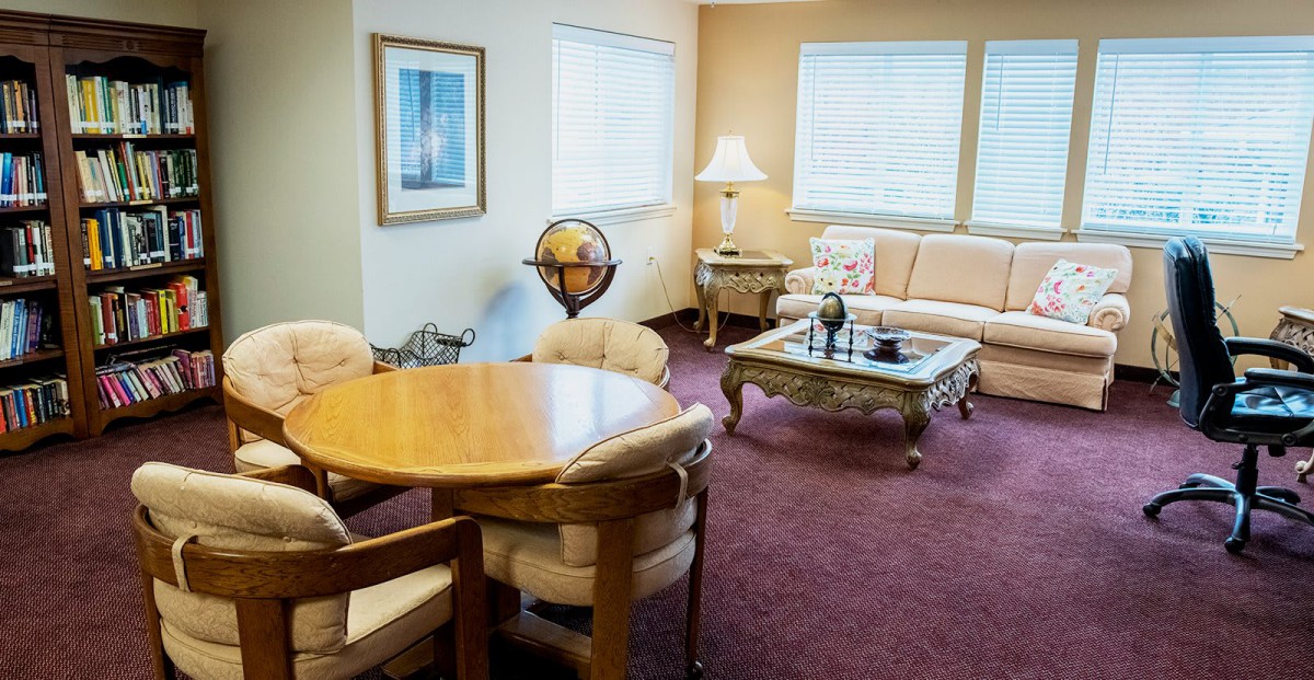 A cozy living room with a sofa, round dining table, globe, and decorative elements in a well-lit setting.