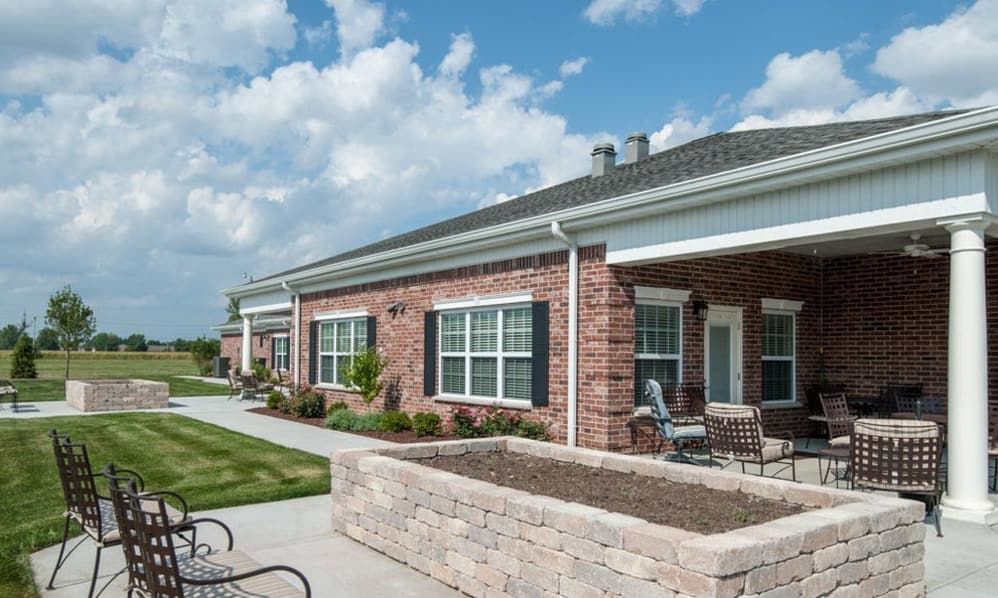 A modern brick residential building with a patio and outdoor seating on a sunny day.