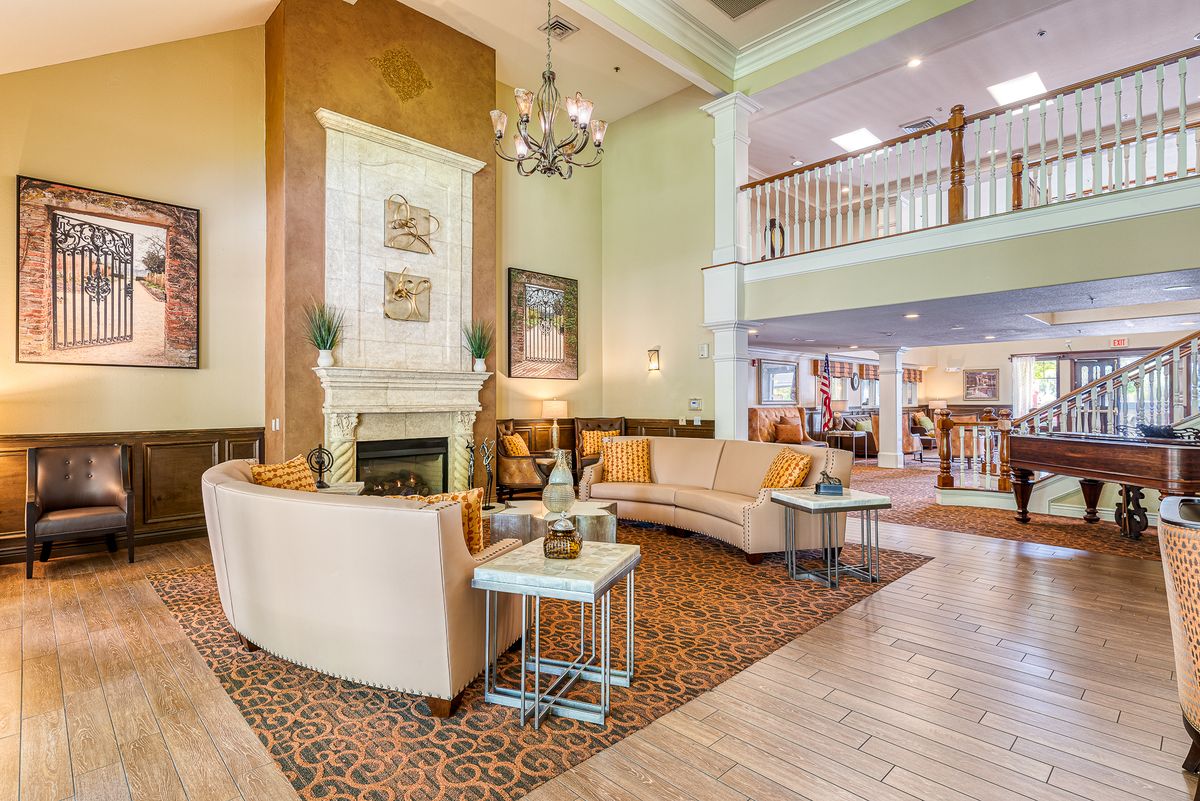 A luxurious hotel lobby featuring elegant seating around a central fireplace, complemented by a chandelier and stylish decor.