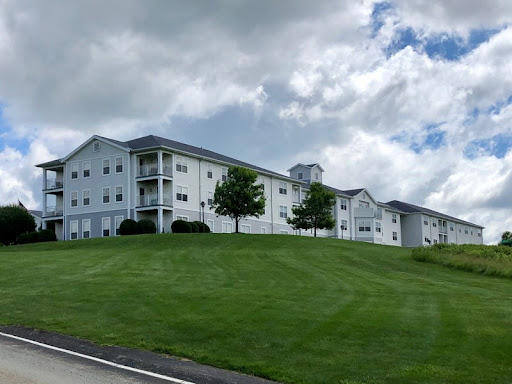 A spacious residential building set against a backdrop of cloudy skies and lush green grass.