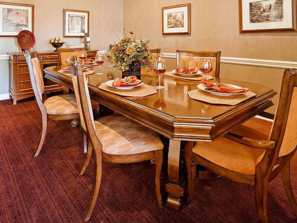A well-decorated dining room with a wooden table and chairs, featuring elegant placemats and wall art.