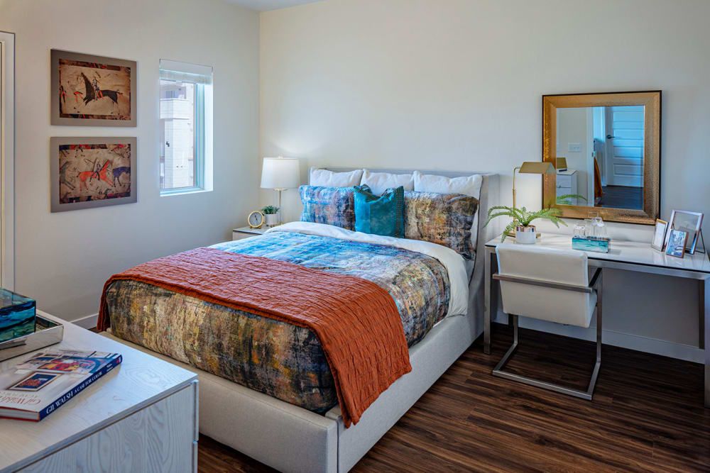 A cozy bedroom with a colorful bedspread, bedside tables, and a desk with a mirror.
