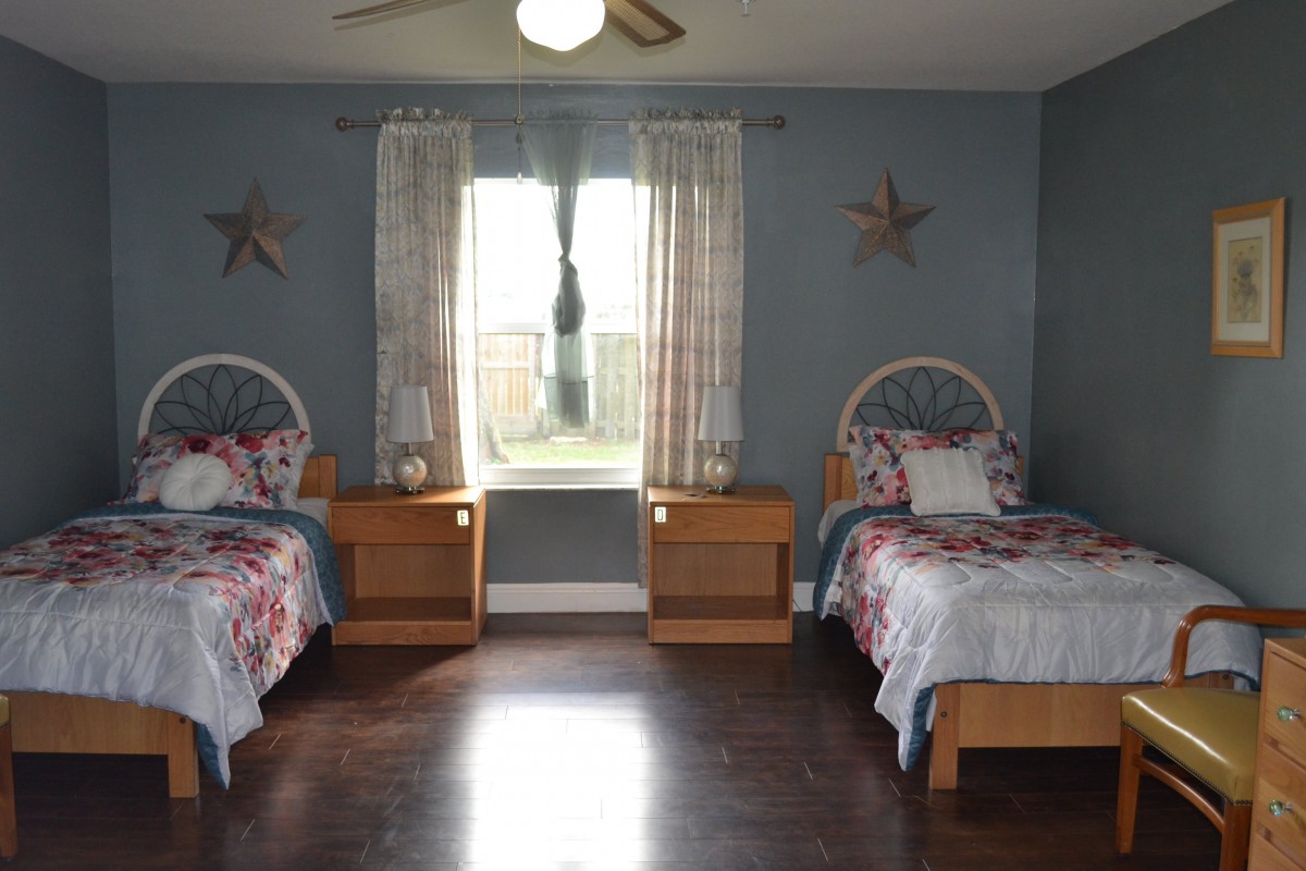 A cozy bedroom with twin beds and a window adorned with star decorations.
