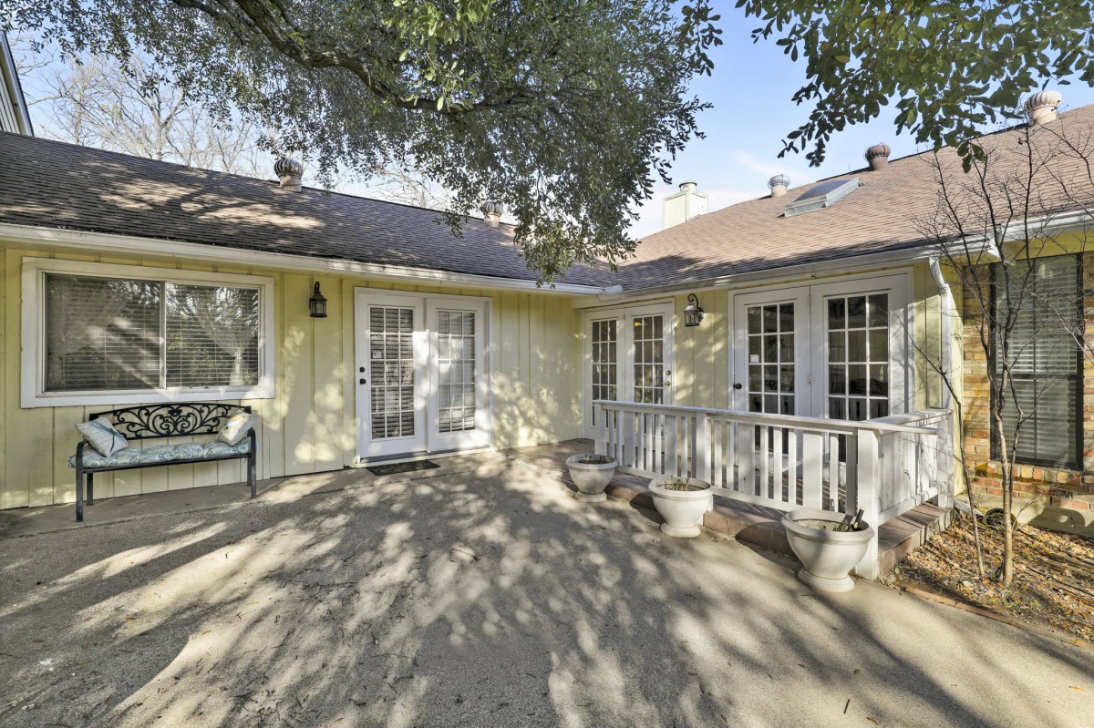 A house exterior with a patio and trees casting shadows.