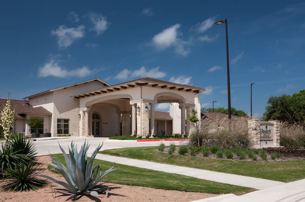 A modern residential building with landscaped surroundings under a clear blue sky.