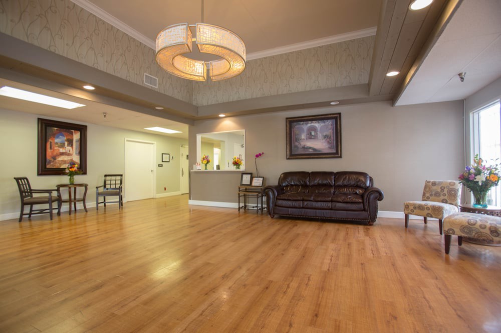 A cozy living room with a sofa, wood flooring, and a large lighting fixture.