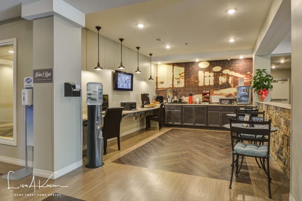 A modern communal kitchen and dining area with computers and a coffee station.