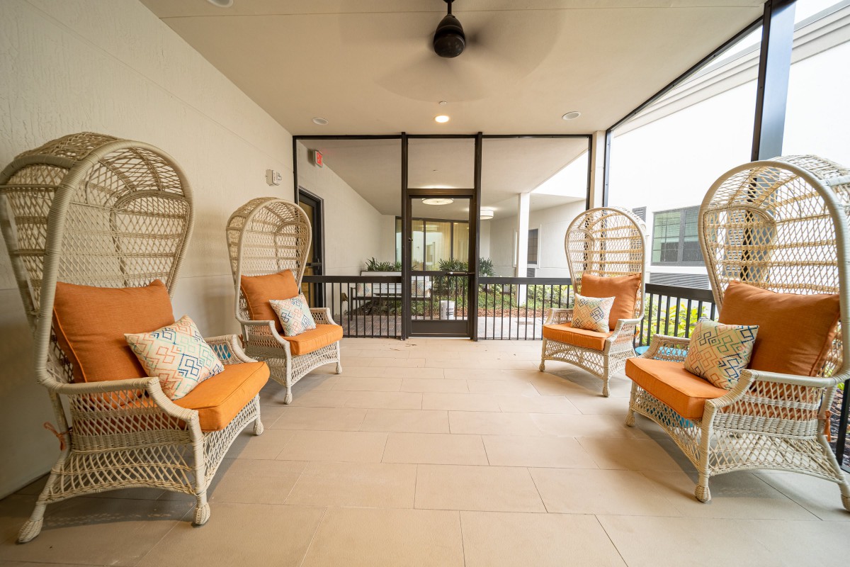 A cozy screened patio with comfortable seating and a ceiling fan.