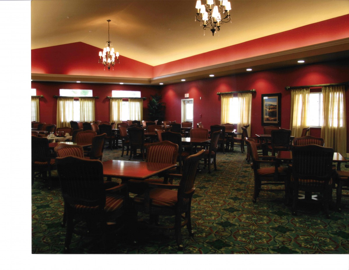 A spacious dining room with elegant chandeliers, red walls, and neatly arranged tables and chairs.