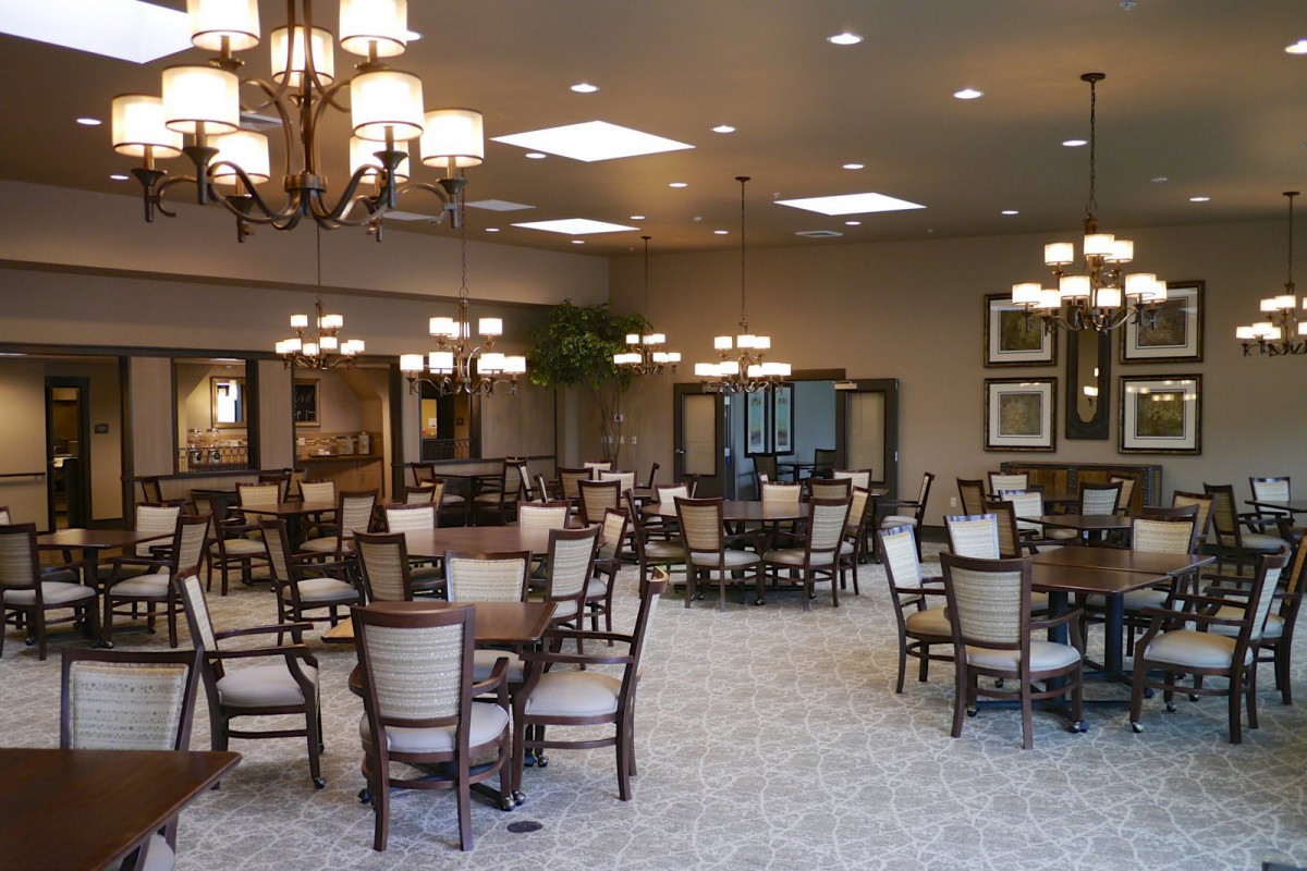 A spacious dining area with neatly arranged tables and chairs, featuring elegant lighting fixtures.