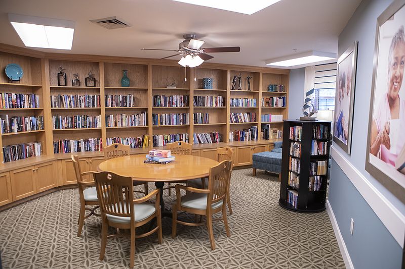 Cozy library space with round table and wooden bookshelves filled with books.