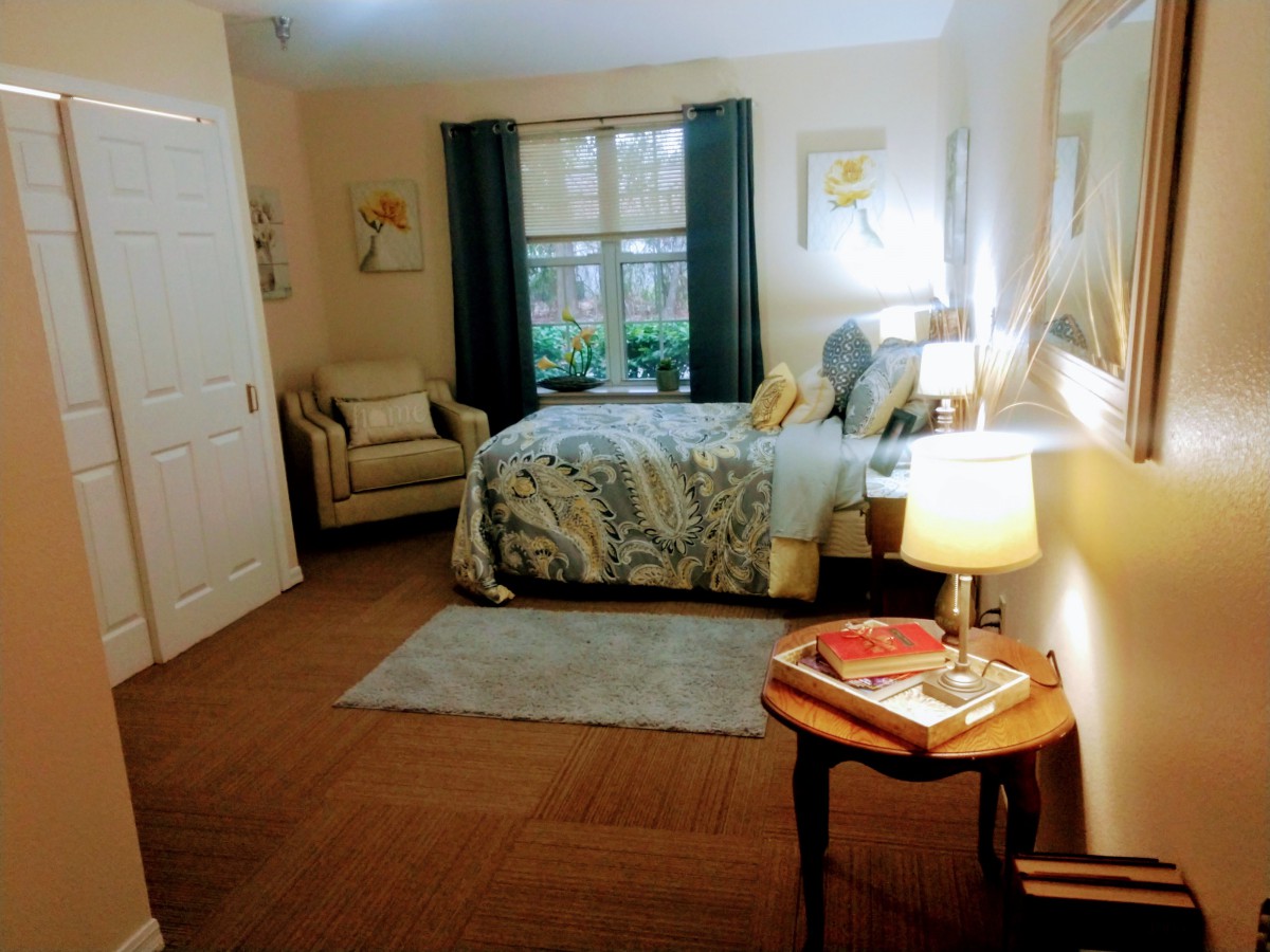 Cozy bedroom with a stylish bed, armchair, and warm lighting.