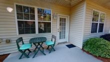 A cozy outdoor patio area with a small table and two chairs, next to a window and door.