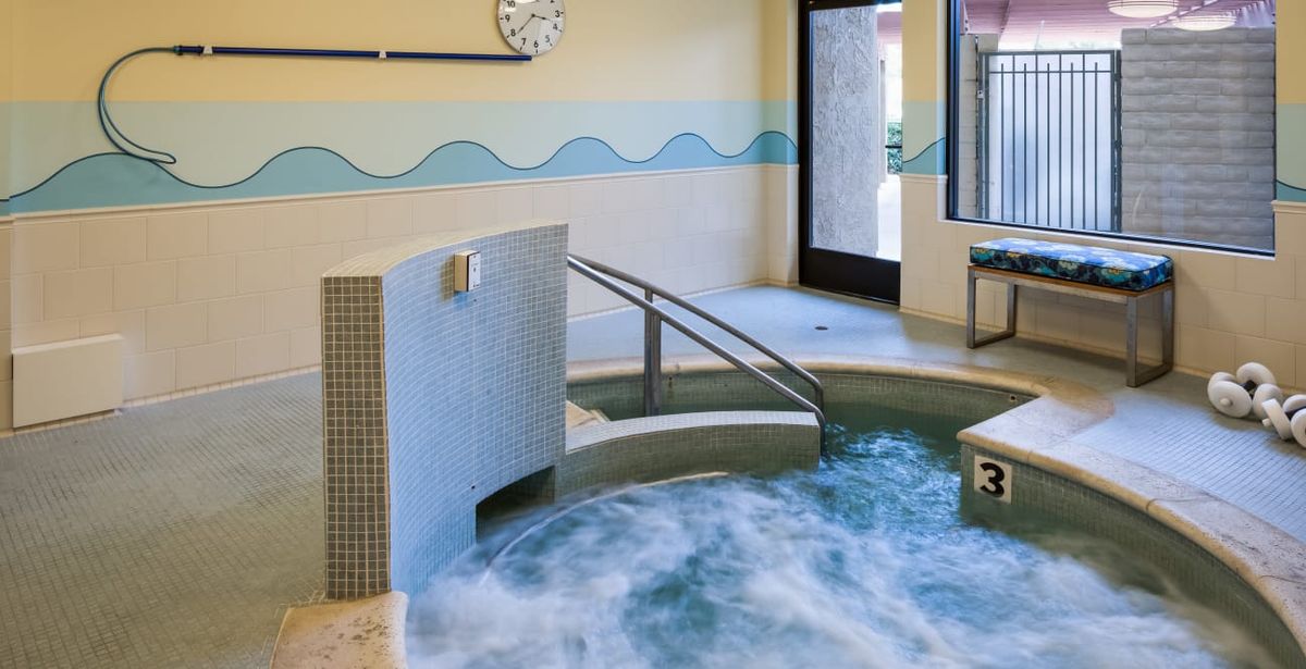 Indoor hot tub area with bubbling water and accessible ramp.