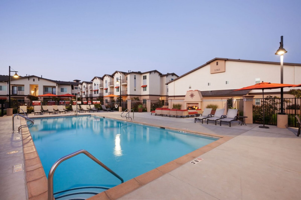 A hotel with an outdoor swimming pool and lounge chairs, perfect for relaxation.
