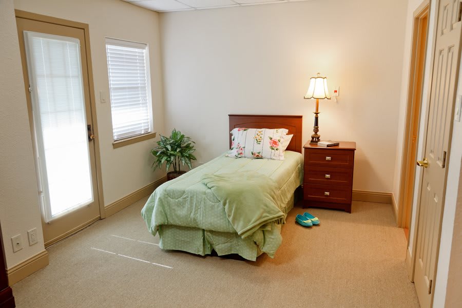 A minimalist bedroom with a single bed, nightstand, and lamp.