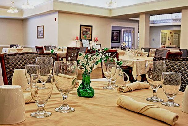 An elegantly set dining table in a restaurant with neatly arranged glasses, napkins, and a small vase centerpiece.