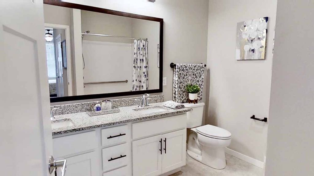 A modern bathroom with a large mirror, sink, and neatly arranged towels.