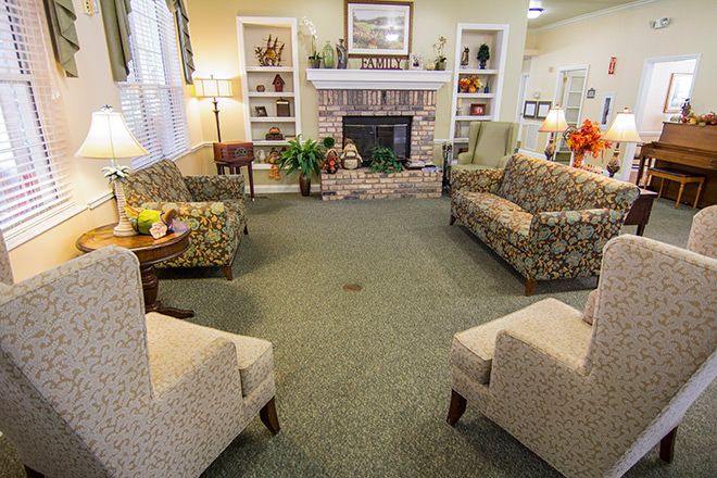 A cozy living room with sofas and chairs arranged around a fireplace.