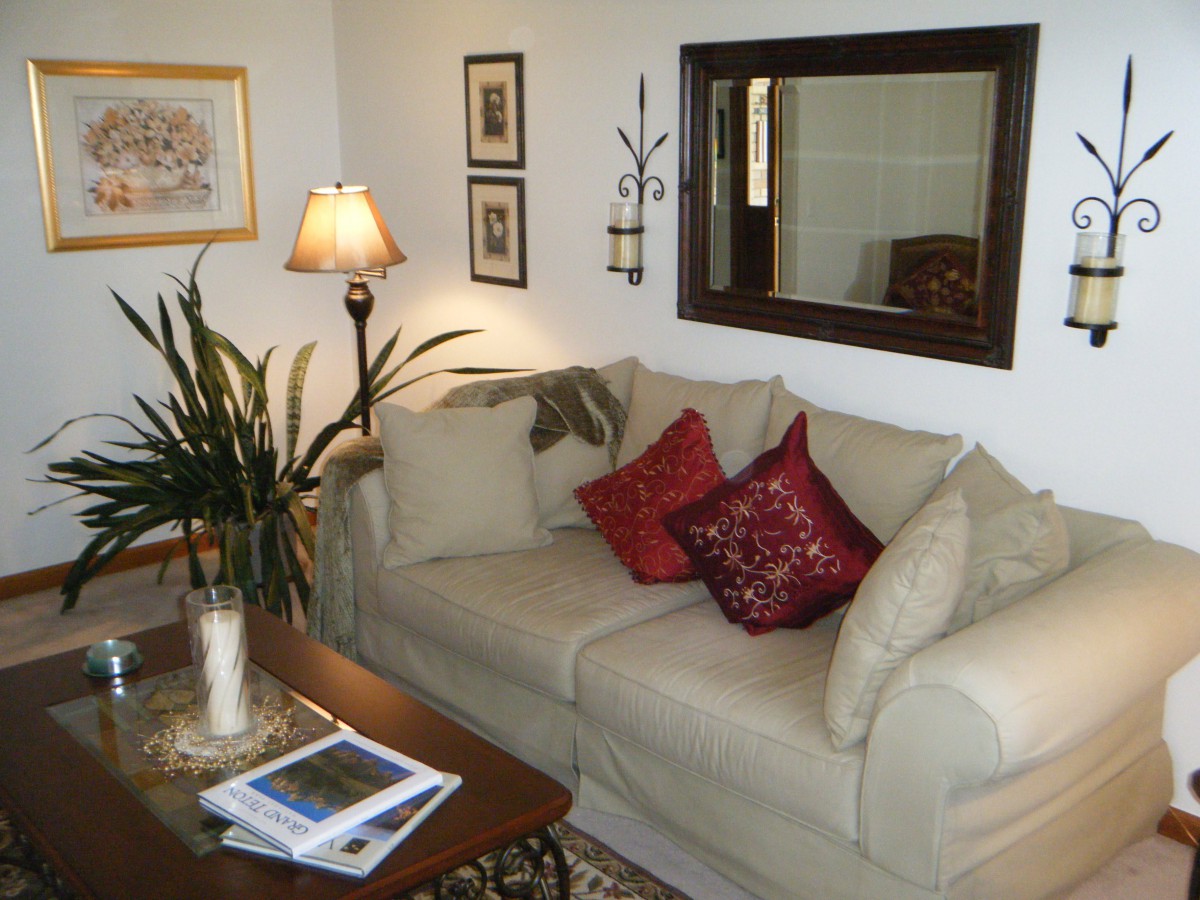 A cozy living room with a beige sofa, decorative cushions, and a warm lamp.