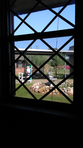 A view through a window showcasing a serene garden with rocks and greenery.