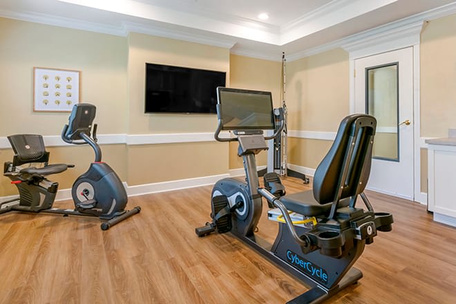 A home gym with exercise bikes and a wall-mounted TV.