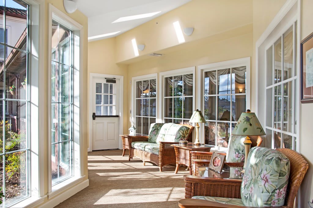 A bright sunroom with comfortable wicker furniture and large windows letting in natural light.