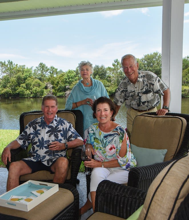 A group of four adults enjoying a relaxing time on a patio with a scenic view.