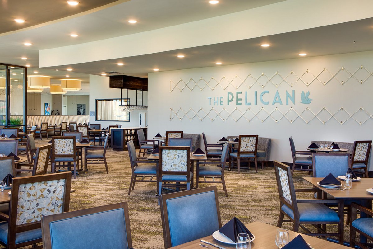 A spacious and modern restaurant interior with neatly arranged tables and chairs, under warm lighting.