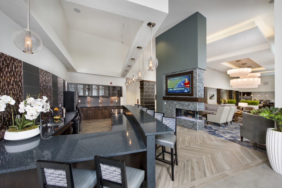 A modern kitchen and bar area with sleek countertops and a wall-mounted television.
