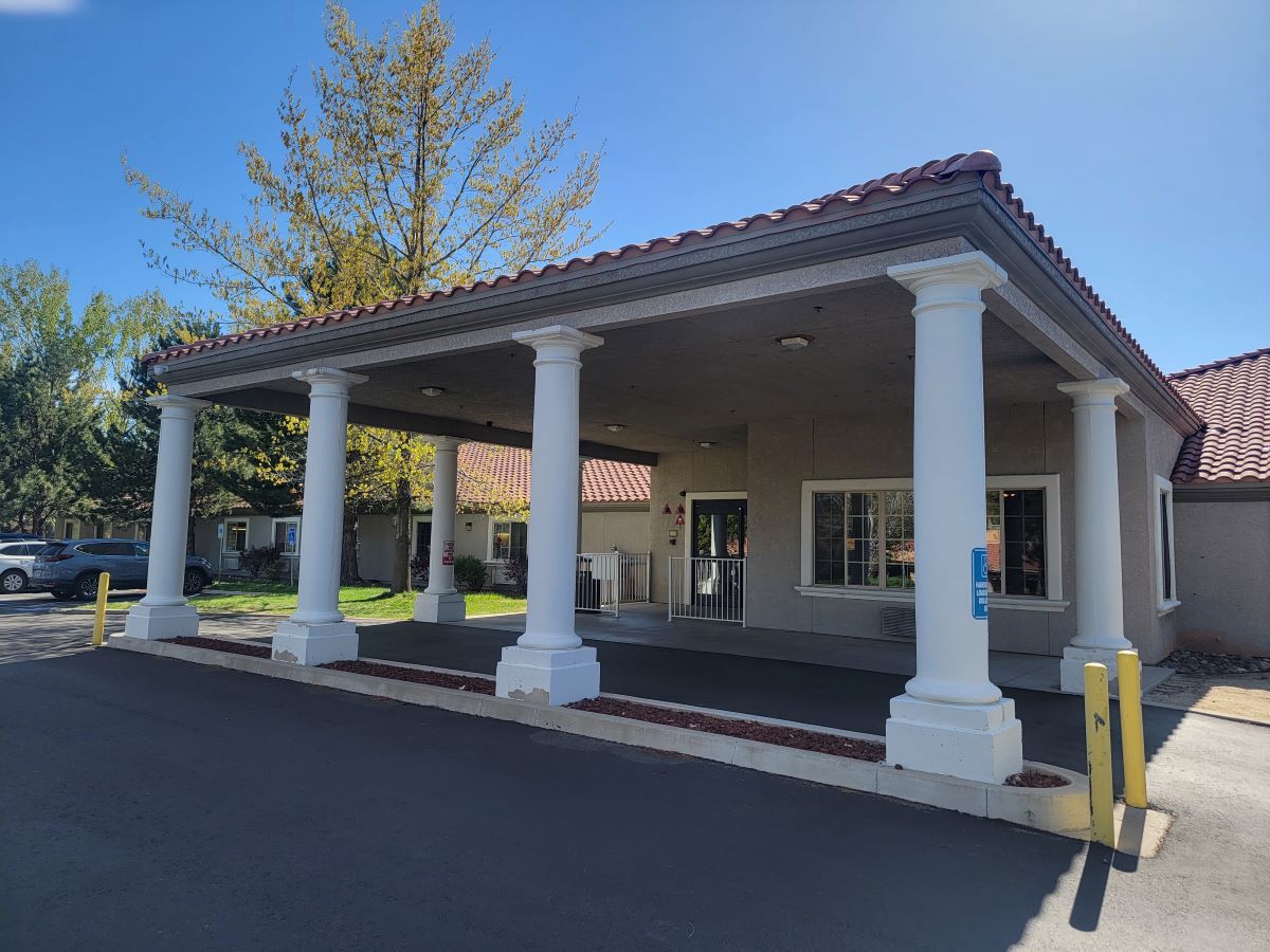 A building entrance with four white columns on a sunny day.