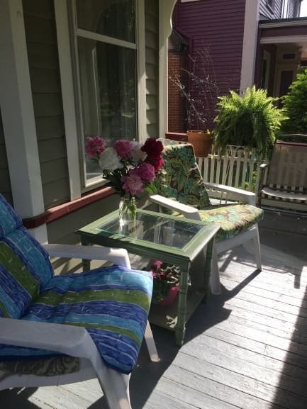 A cozy patio with chairs and a table adorned with flowers, basking in sunlight.
