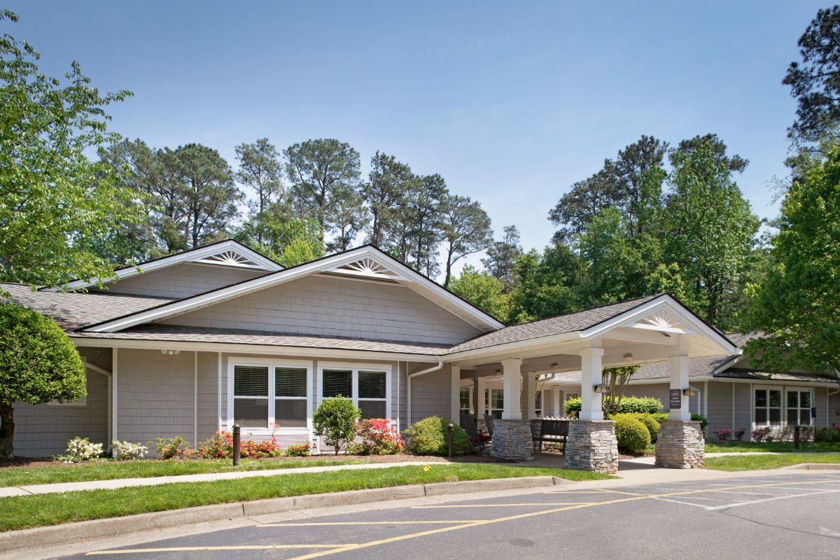 A residential building surrounded by trees and landscaping on a clear day.