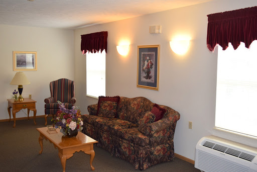 A cozy living room featuring a floral-patterned couch, an armchair, and a wooden coffee table.