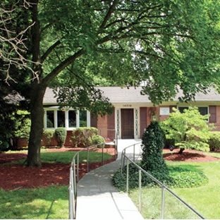 A suburban house with a landscaped front yard and a tree-lined pathway.