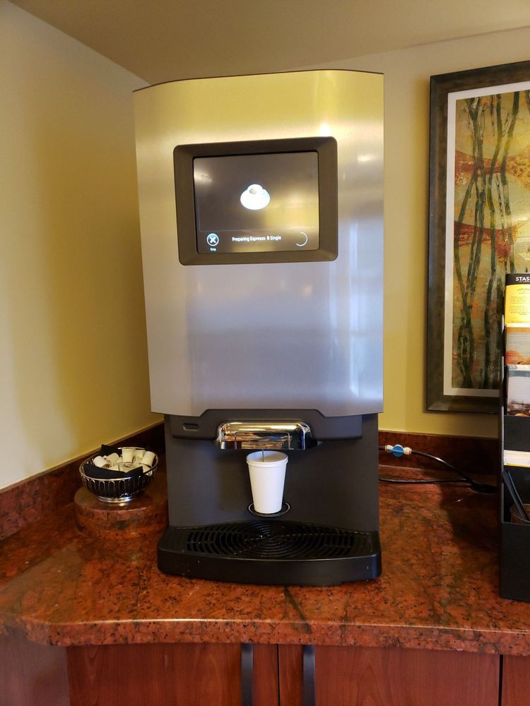 A self-service coffee machine in a hotel lobby ready to dispense a hot beverage.