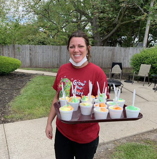 A woman happily serving colorful desserts on a tray in a garden setting.