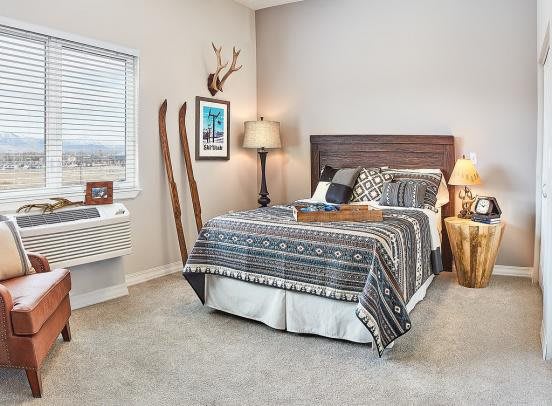 A cozy rustic bedroom featuring a stylish bed with patterned bedding, decorative wall art, and vintage skis as part of the decor.