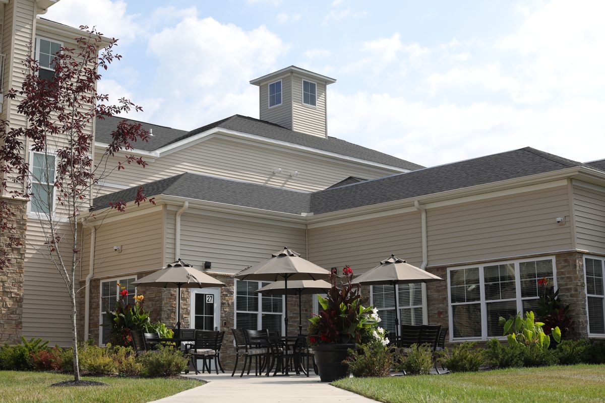 A modern building with a patio area featuring several umbrellas.