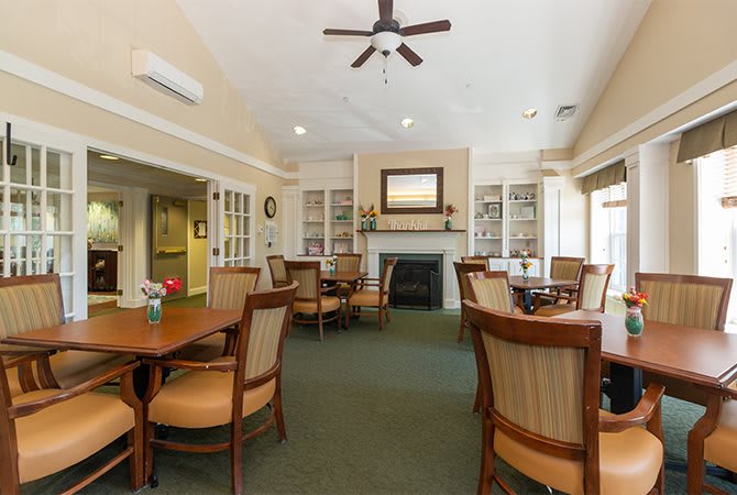 An inviting dining area with tables, chairs, and a central fireplace.